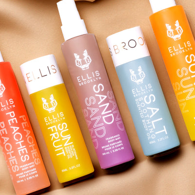 Peaches Hair And Body Fragrance Mist 100ml, Sun Fruit 95ml Glistening Golden Scented Body Oil, Sand Hair And Body Fragrance Mist 100ml, Salt 95ml Soothing Scented Body Oil, and Sun Hair And Body Fragrance Mist 100ml, on brown background.