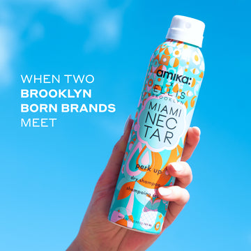 Model with white nail polish holding Amika x Ellis Brooklyn Miami Nectar Perk Up Dry Shampoo against blue sky with white text that reads "When Two Brooklyn Born Brands Meet"