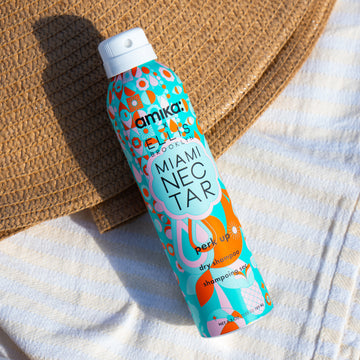 Amika x Ellis Brooklyn Miami Nectar Perk Up Dry Shampoo on yellow and white striped beach towel and tan straw hat.