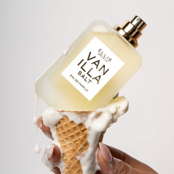 Model with nude nail polish holding ice cream cone with melted vanilla ice cream and Vanilla Salt 50ml Eau De Parfum without cap on white background.