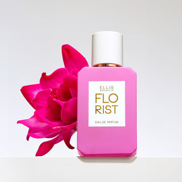 Florist 50ml perfume bottle with pink flower on grey background.