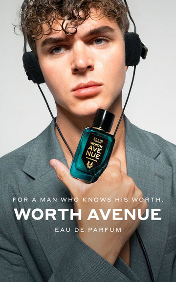 Model with brown hair wearing gray jacket and headphones holding Worth Avenue 50ml Eau De Parfum to chin, on white background above white text that reads "For A Man Who Knows His Worth. Worth Avenue Eau De Parfum"