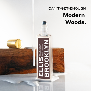 Milk Wood Fragrance Oil 15ml with cap removed in puddle of milk in front of piece of wood with milk being poured on it on white background below black text that reads "Cant-Get-Enough Modern Woods."