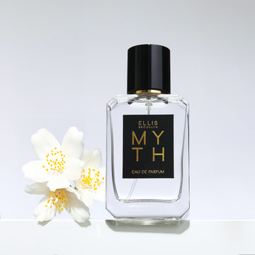 Myth 50ml bottle with white and yellow flowers on a grey background.