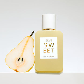 Sweet 50ml perfume bottle with sliced pear on grey background.