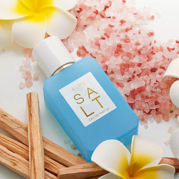 Salt 50ml Eau De Parfum with pink salt, sandalwood, and white and yellow flowers on white background.