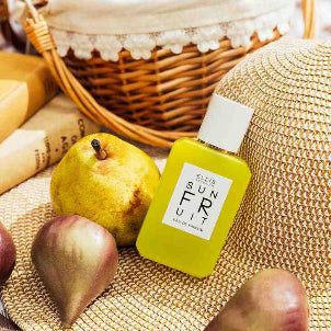 Sun Fruit 50ml bottle on a straw hat with 3 pears and a picnic basket in the background.