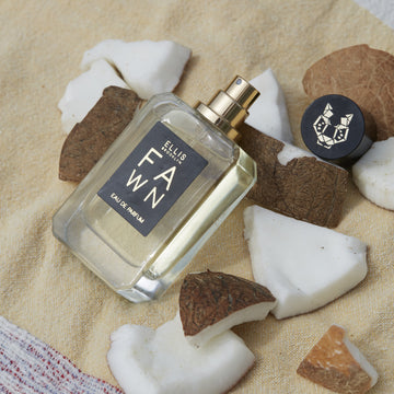 Fawn 50ml Eau De Parfum with cap removed resting on pieces of coconut on yellow towel.