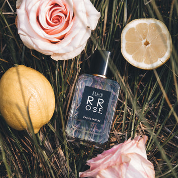 Rrose 50ml Eau De Parfum on grass with lemons and pink roses.