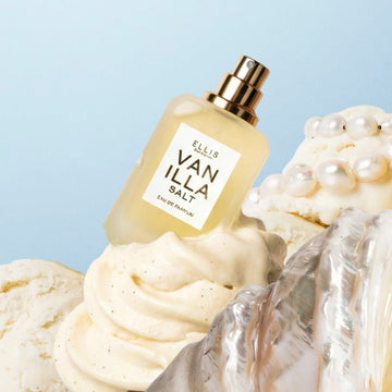VANILLA SALT Eau de Parfum 7.5ml without cap behind silver shell on vanilla ice cream with pearls on top on a blue background