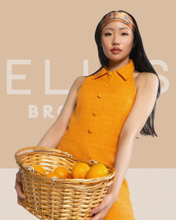 Woman with black hair wearing orange dress and orange and blue floral headband holds a tan basket of oranges on tan background that reads "Ellis Brooklyn"