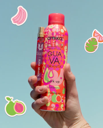 Hand wearing gold bracelets holds Amika x Ellis Brooklyn GUAVA GRANITA Perk Up Dry Shampoo and GUAVA GRANITA Eau de parfum 10ml on blue background with drawn pink bananas, pink and orange orange slice, green and pink palm leaf, and green and pink guavas all outlined in white