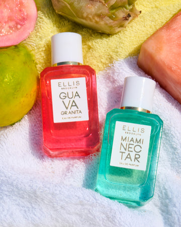 Half guava, whole guava, whole pineapple, and slice of pink pineapple on yellow and white striped beach towel above Guava Granita 7.5ml Eau De Parfum Mini Dabber next to Miami Nectar 7.5ml Eau De Parfum Mini Dabber.