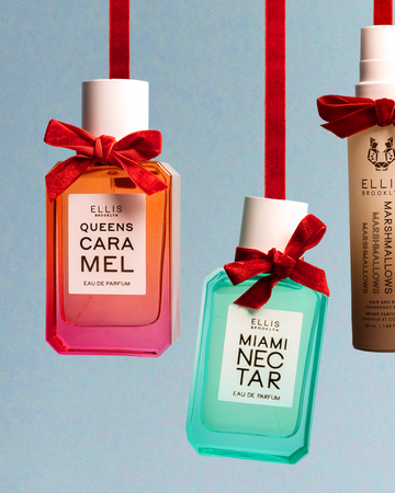 Queens Caramel 50ml Eau De Parfum, Miami Necta 50ml Eau De Parfum, and Marshmallows 50ml Hair and Body Fragrance mist each tied near nozzle with red bow and hanging, on blue background.