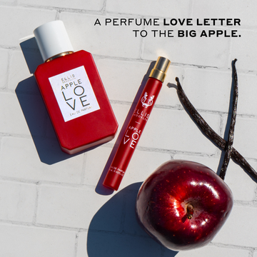 Apple Love 50ml Eau De Parfum, Apple Love 10ml Eau De Parfum Travel Spray, red apple, and vanilla beans on white tile with black text that reads "A perfume love letter to the big apple."