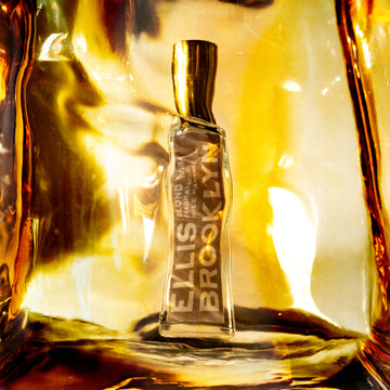 Huile parfumée Blond Musk (15 ml) placée derrière un bloc d'ambre.