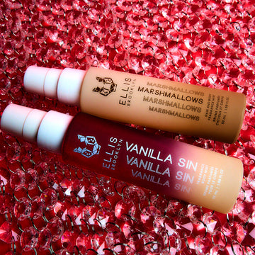 Marshmallows 50ml Hair and Body Fragrance Mist and Vanilla Sin 50ml Hair and Body Fragrance Mist resting on top of diamond chains, on red background.