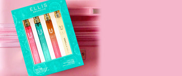 FIRST CLASS Gift Set containing GUAVA GRANITA Eau de Parfum 10ml, MIAMI NECTAR Eau de Parfum 10ml, QUEENS CARAMEL Eau de Parfum 10ml, and VANILLA SALT Eau de Parfum 10ml in front of a pink suitcase zipper