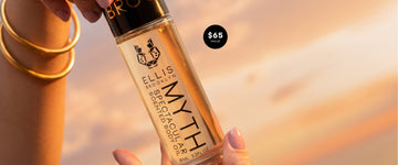 Hands with pink manicure and wearing gold bracelets hold MYTH Spectacular Scented Body Oil against sunset sky with  white text in black circle that reads "$65 Value"