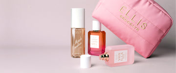 Pink Cosmetic Bag with gold embroidery that reads "Ellis Brooklyn" propped up on QUEENS CARAMEL Eau de Parfum 50ml, next to MARSHMALLOWS Perfume Mist 90ml, and behind VANILLA RICE Eau de Parfum 50ml without cap laying down next to cap on gray background