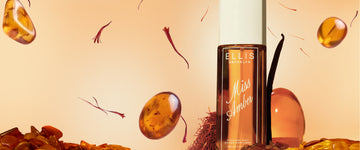 240mL Miss Amber Perfume Mist bottle standing with a vanilla bean, red saffron, and amber colored stones on yellow background