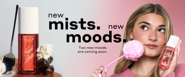 FIRST DATE Perfume Mist 90ml next to whipped cream, a spoon leaning against the bottle, a stack of 2 dates and whipped cream on date syrup and a model with blonde hair in a pink sweater looks up and holds MISS STRAWBERRY Perfume Mist 90ml against one cheek and a pink pen with a pink pompom on the end against the other cheek with black text that reads "new mists. new moods. Two new moods are coming soon." all on a white and pink ombré background.