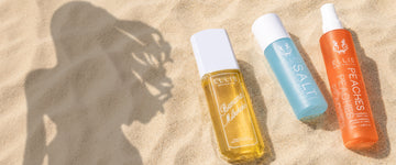 BANANA MILKSHAKE Perfume Mist 240ml, SALT Body Oil, PEACHES Perfume Mist 100ml without cap lay on sand with the shadow of a woman 