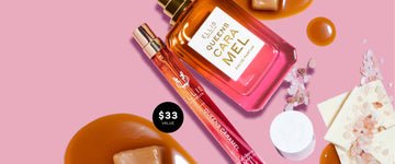 Queens Caramel 10ml Eau De Parfum Travel Spray next to Queens Caramel 50ml Eau De Parfum with cap removed and melted caramel, caramel squares, pieces of white chocolate, pink salt, and a cap on a pink background with a black circle and white text that reads "$33 Value"