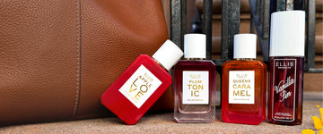 Apple Love eau de parfum 50mL, Plum Tonic eau de parfum 50mL, Queens Caramel eau de parfum 50mL and Vanilla Sin perfume mist 90mL displayed against a brown leather bag on outdoor stone steps.