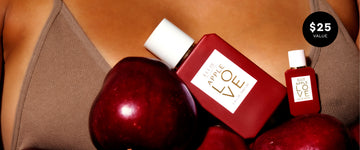 A person wearing a brown ribbed top, holding red apples beside one 50mL botte of APPLE LOVE eau de parfum next to a mini 7.5mL bottle of APPLE LOVE eau de parfum with a black '$25 VALUE' badge in the top right.