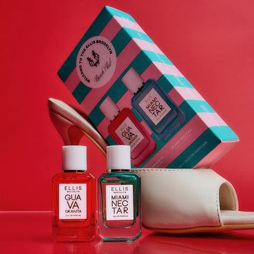 Beach Club Mini Fragrance Duo Gift Set box resting in white heeled sandal next to Guava Granita 7.5ml Eau De Parfum Mini Dabber and Miami Nectar 7.5ml Eau De Parfum Mini Dabber on bright pink background.