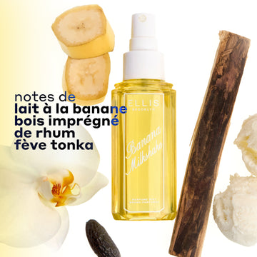 Brume Parfumée BANANA MILKSHAKE 240ml sans bouchon entourée de 2 tranches de banane, un morceau de bois de rhum, 2 boules de glace à la vanille, une fève tonka et une fleur sur un fond ombré blanc et jaune avec un texte noir indiquant « notes de lait a la banane, bois imprègnè de rhum fève tonka »