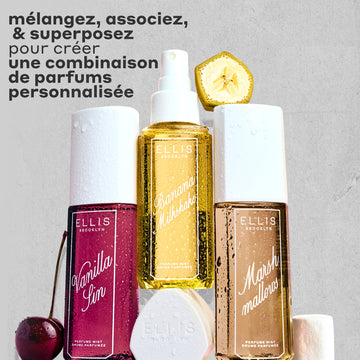 Brume Parfumée VANILLA SIN 240ml à côté d'une cerise, Brume Parfumée BANANA Milkshake 240ml posée sur son bouchon, Brume Parfumée MARSHMALLOWS 240ml avec une tranche de banane dessus et une guimauve à côté, le tout couvert de gouttes d'eau sur un fond gris et rugueux avec un texte noir qui dit « Mélangez, associez et superposez pour créer une combinaison de parfums personnalisée. »