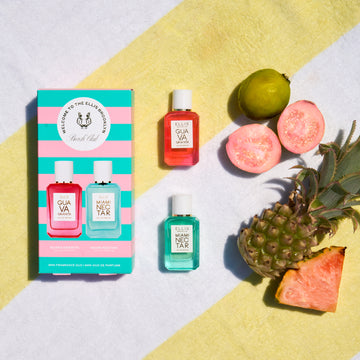Pink pineapple slice, whole pineapple, cut guava, whole guava, Guava Granita 7.5ml Eau De Parfum Mini Dabber, Miami Nectar 7.5ml Eau De Parfum Mini Dabber and Beach Club Mini Fragrance Gift Set Box on white and yellow striped beach towel.