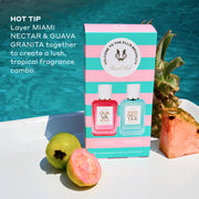 Beach Club Mini Fragrance Gift Set box on white table with whole guava, half guava, whole pineapple, and slice of pink pineapple with pool in background, and white text that reads  "Hot Tip Layer Miami Nectar and Guava Granita Together To Create A Lush Tropical Fragrance Combo."