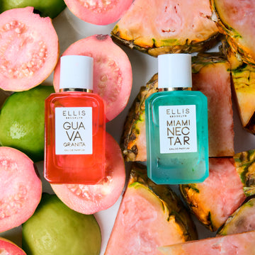 Guava Granita 7.5ml Eau De Parfum Mini Dabber resting on cut guavas next to Miami Nectar 7.5ml Eau De Parfum Mini Dabber resting on slices of pink pineapple, on white background.