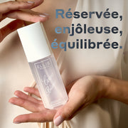 Brume parfumée COCOA BLANCO 90 ml tenue entre les mains d’une femme contre un haut en satin crème, avec un texte bleu foncé qui indique « réservée, enjoleuse, équilibrée. »