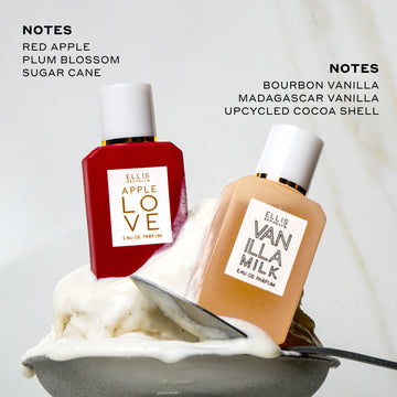 Apple Love 7.5ml Eau De Parfum Mini Dabber and Vanilla Milk 7.5ml Eau De Parfum Mini Dabber in small bowl with vanilla ice cream and spoon on marble background under black text that reads "Notes Red Apple Plum Blossom Sugar Cane" and "Notes Bourbon Vanilla Madagascar Vanilla Upcycled Cocoa Shell".