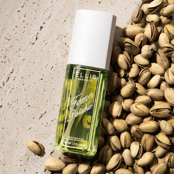 Brume Parfumée FOREVER PISTACHIO 90ml sur marbre beige et tas de pistaches