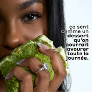 Femme aux cheveux noirs portant une bague en diamant et tenant un gâteau vert avec un glaçage blanc sur un fond blanc avec un texte en noir et gris qui dit « ça sent comme un dessert qu'on pourrait savourer toute la journée. »