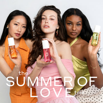 Woman with black hair wearing an orange dress and white pearl earrings holds NEW CRUSH Perfume Mist 90ml, woman with brown hair wearing a pink off the shoulder top and pink earrings holds LOVE POM Perfume Mist 90ml, and woman with brown hair wearing green tank top, gold bracelet and white and black polka dot skirt holds FOREVER PISTACHIO Perfume Mist 90ml on a white background with white text that reads "the SUMMER OF LOVE trio"