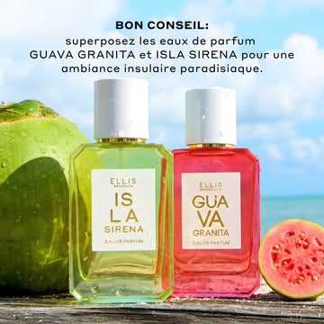 L'Eau de Parfum ISLA SIRENA 50ml est posée à côté de l'Eau de Parfum GUAVA GRANITA 50ml entre une noix de coco verte et une moitié de goyave tranchée, le tout recouvert de gouttes d'eau sur un bois brun avec un ciel bleu et des nuages blancs en arrière-plan et un texte noir qui dit : 'Bon Conseil: Superposez les eaux de parfum GUAVA GRANITA et ISLA SIRENA pour une ambiance insulaire paradisiaque.'
