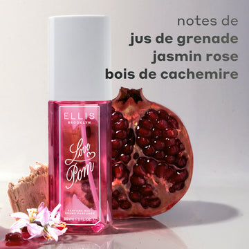 Brume parfumée LOVE POM 90ml entre fleur blanche, jus de grenade, bois et une moitié de grenade sur fond blanc avec texte gris indiquant « notes de jus de grenade, jasmin rose, bois de cachemire »