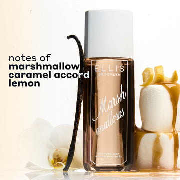 MARSHMALLOWS Perfume Mist 240ml between 2 stacked marshmallows covered in dripping caramel and topped with a lemon peel and a vanilla bean and flower leaning against the bottle on a white background with black text that reads "notes of marshmallow, caramel accord, lemon"