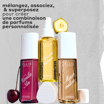 Brume Parfumée VANILLA SIN 240ml à côté d'une cerise, Brume Parfumée BANANA Milkshake 240ml posée sur son bouchon, Brume Parfumée MARSHMALLOWS 240ml avec une tranche de banane dessus et une guimauve à côté, le tout couvert de gouttes d'eau sur un fond gris et rugueux avec un texte noir qui dit « melangez, associez et superposez pour creer une combinaison de parfums personnalisé. »