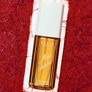 Miss Amber perfume mist 90mL bottle with an amber glass body and a white cap, set against a textured red and white background.
