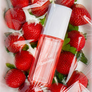 MISS STRAWBERRY Brume Parfumée 90ml posée sur des fraises sur une surface blanche, le tout recouvert de plastique transparent