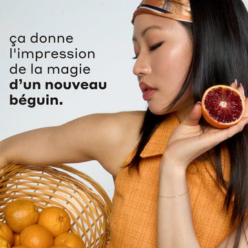 Femme aux cheveux noirs portant un bandeau et un débardeur orange et bleu tient un panier beige rempli d'oranges et d'une orange sanguine tranchée sur fond blanc avec du texte noir qui dit « ca donne I'impression de la magie d'un nouveau beguin. »