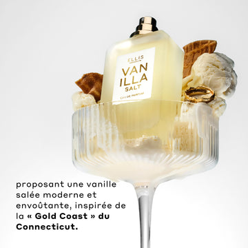 Vanilla Salt 50ml Eau De Parfum sans bouchon dans un verre avec glace à la vanille, morceaux de cône de glace, et bague en or, sur fond blanc, au-dessus d’un texte noir qui dit « Proposant une vanille salee moderne et envoutante, inspirée de la Gold Coast du Connecticut. »