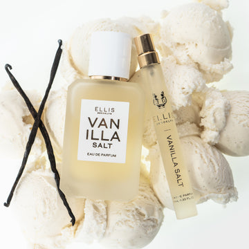 Vanilla beans, Vanilla Salt 50ml Eau De Parfum, and Vanilla Salt 10ml Eau De Parfum Travel Spray resting on scoops of vanilla ice cream, on white background.